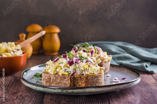 Swedish salad with anchovies, potatoes and egg on rye bread on a plate