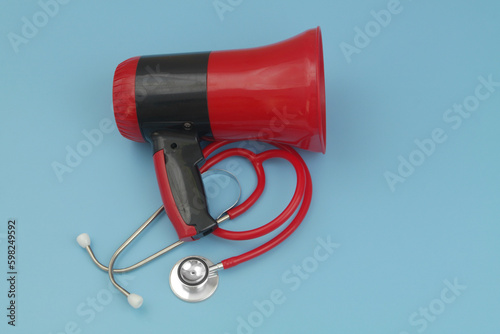 Loudspeaker with red stethoscope on blue. Hire medical workers concept. 