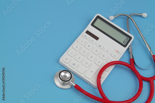 Close-up of red stethoscope and white calculator with copy space for text.
