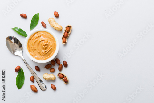 Bowl of peanut butter and peanuts on table background. top view with copy space. Creamy peanut pasta in small bowl