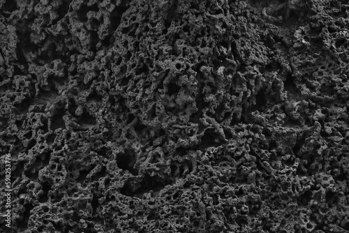 Dark abstract texture of rough rock texture. Sandy wrinkled background in the dark, black surface
