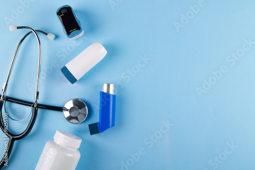 Top view of stethoscope, oximeter, bottle of pills and inhalers on blue background with copy space. Concept of Breathing trouble caused by asthma photo