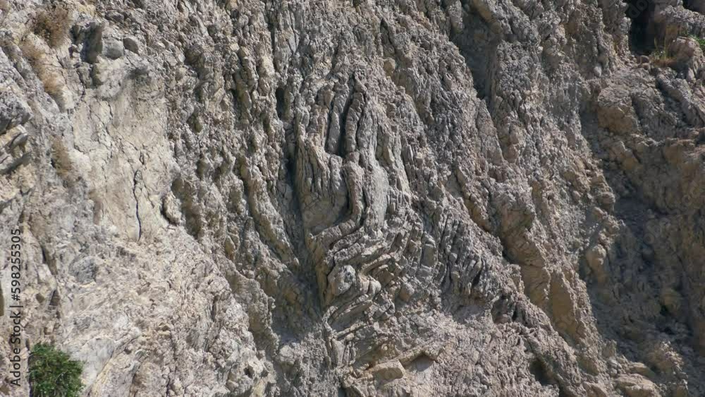 Mediterranean seascape, a fancy pattern of volcanic rocks on a coastal cliff, reverse zoom. Mediterranean seascape, a fancy pattern of volcanic rocks on a coastal cliff, reverse zoom.