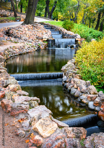 Obraz na płótnie Stones bordered stream and small artificial waterfalls at Bastion Hill park in autumn city park at Riga, Latvia. w salonie