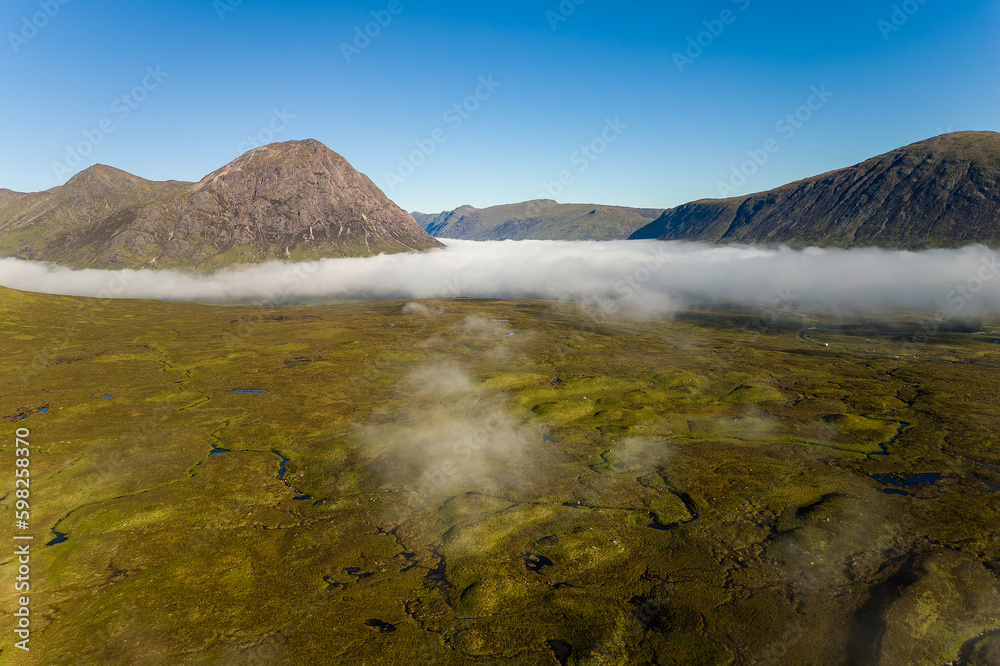 Aerial view of mountain peaks rising above low lying fog in a deserted valley (Glencoe, Highlands, Scotland)