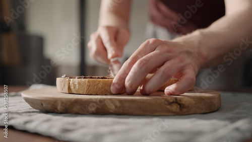 Man spreading chocolate cream on bread slice