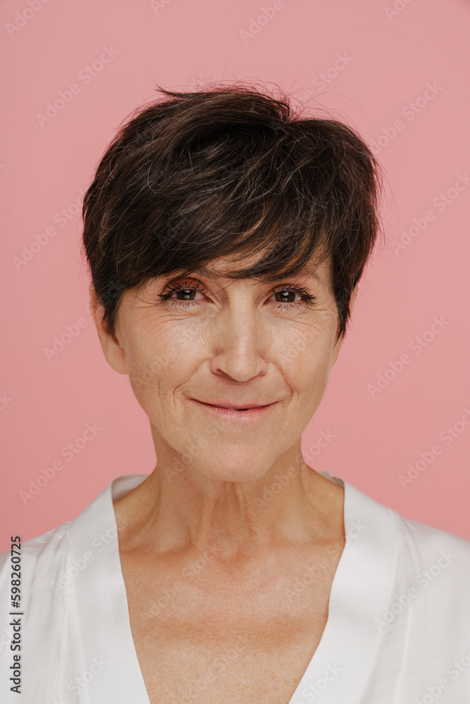 Senior woman smiling at camera while standing isolated over pink background Senior woman smiling at camera while standing isolated over pink background