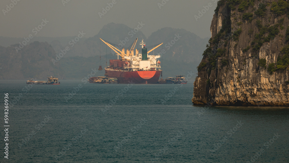 Obraz premium General cargo ships and bulk carriers transporting dry loose cargo anchored in Ha Long Bay in Vietnam, Southeast Asia