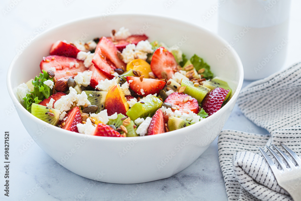 Fruit salad with feta and seeds in white bowl on white table. Healthy vegan detox summer recipe. Fruit salad with feta and seeds in white bowl on white table. Healthy vegan detox summer recipe.