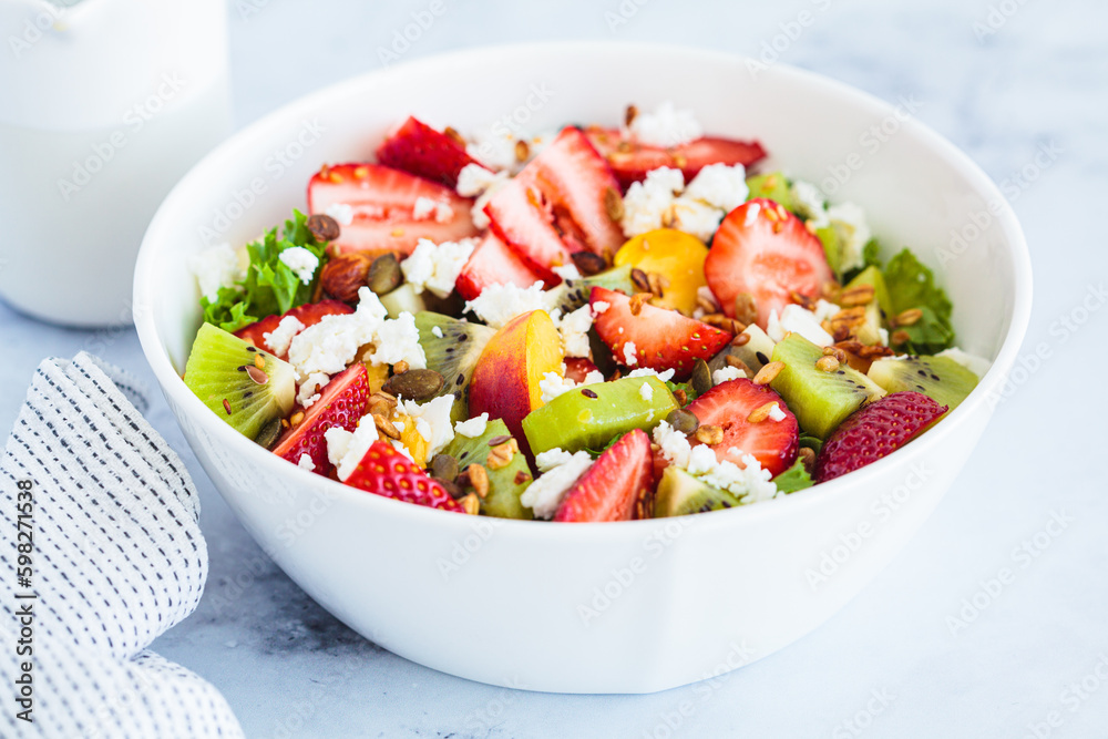 Fruit salad with feta and seeds in white bowl on white table. Healthy vegan detox summer recipe. Fruit salad with feta and seeds in white bowl on white table. Healthy vegan detox summer recipe.