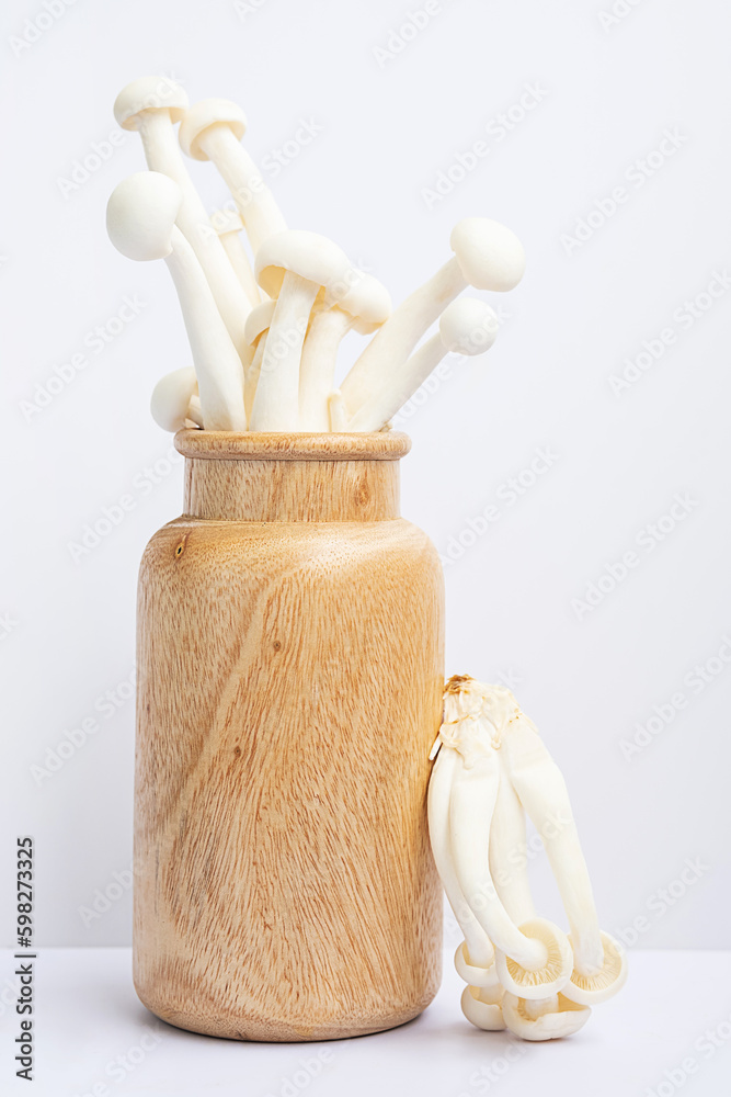 Mushrooms conceptual still life. White beech or shimeji mushrooms in wooden vase.
