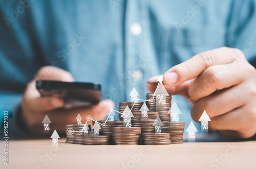 Businessman holding coins stacking with up arrow for financial banking interest rate from money saving and business investment growth from dividend concept.