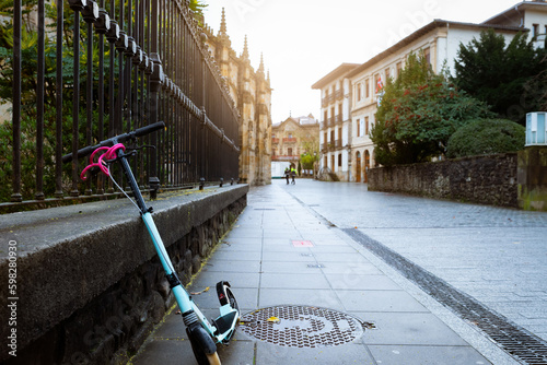 Electric scooter bike lean on concrete wall beside street in Europe. Eco transport on old city road. Urban lifestyle. Future transportation. Sustainable lifestyle. Historical building architecture. photo