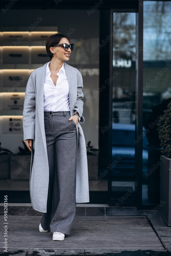 Beautiful business woman in grey coat outside office building