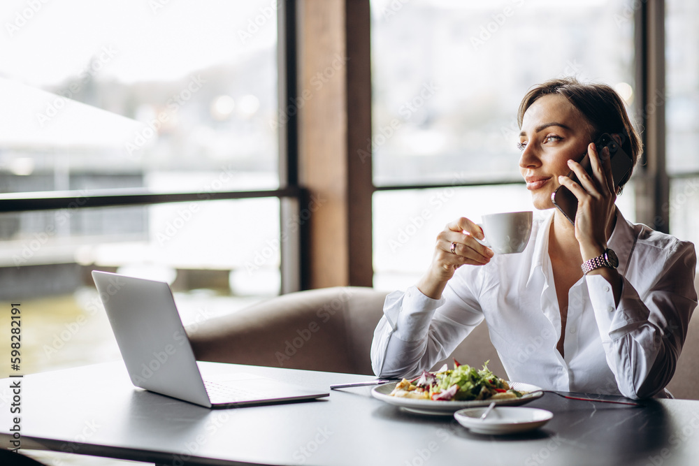 Business woman working on laptop and eating salad Business woman working on laptop and eating salad