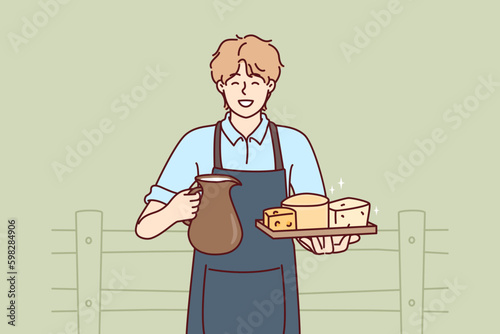 Man holds jug of milk and tray of cheese from cow farm selling own organic food. Guy wearing apron working on cow farm offers to buy organic dairy products with useful nutritional Generative AI