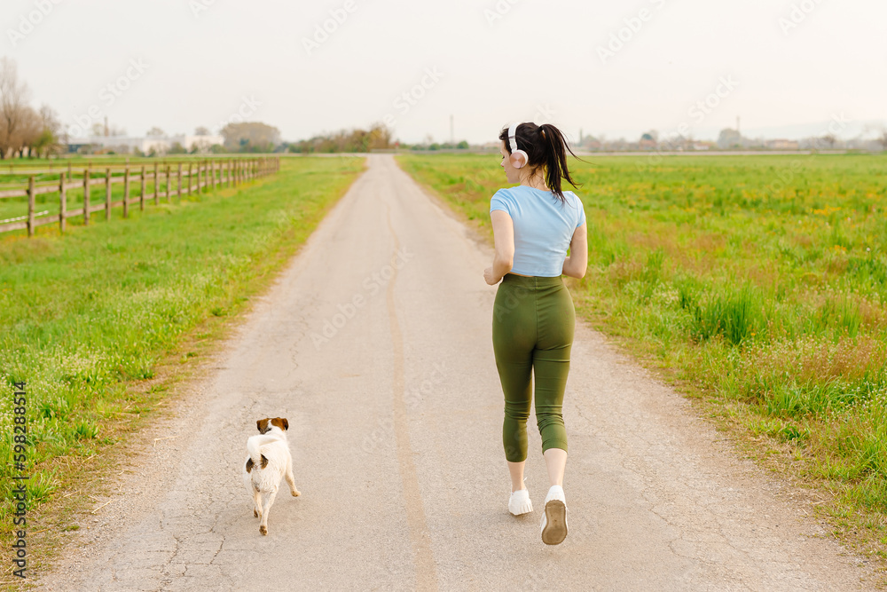 Woman and dog running and exercising outdoor at grass field on summer or spring. Happy female athlete training with her pet. Woman and dog running and exercising outdoor at grass field on summer or spring. Happy female athlete training with her pet.