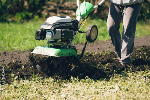 Farmer man plows the land with a cultivator preparing the soil for sowing