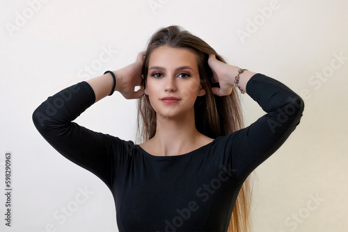Front view of attractive brunette girl posing with hands in her hand on the light background. Horizontally. 