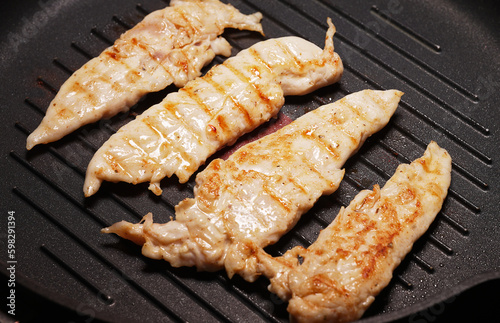 Pieces of chicken fillet are fried in a grill pan.