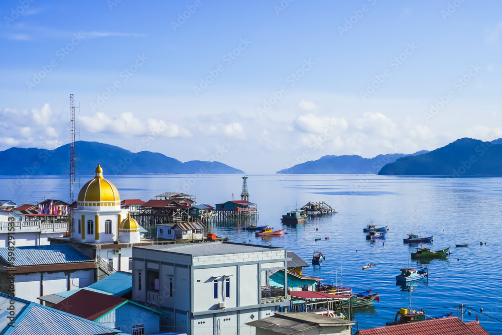 Tarempa, Anambas Archipelago, Riau Islands, Indonesia seen from the top of many buildings against a backdrop of blue ocean, fisherman fishing boats, islands, white clouds, clear sky in the morning.