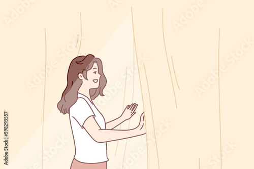 Smiling woman looks out window opening curtains and enjoying rays of summer morning sun. Girl opens curtains rejoicing at new sunny day after waking up in morning or dreams of going for Generative AI