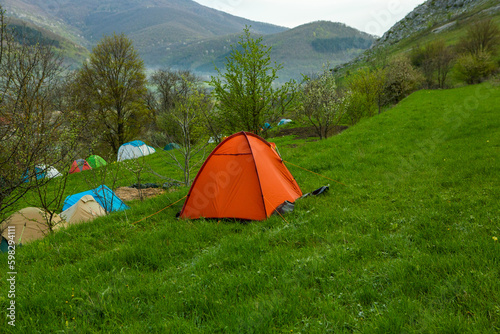 Camping tents on a green meadow in the mountains in spring. Rest with the tent in nature