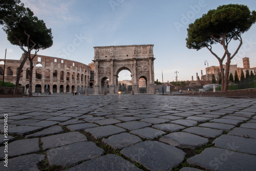 Rome, Italy, Constantine Arch and the Colosseum at sunrise, low angle with focus on the cobblestones