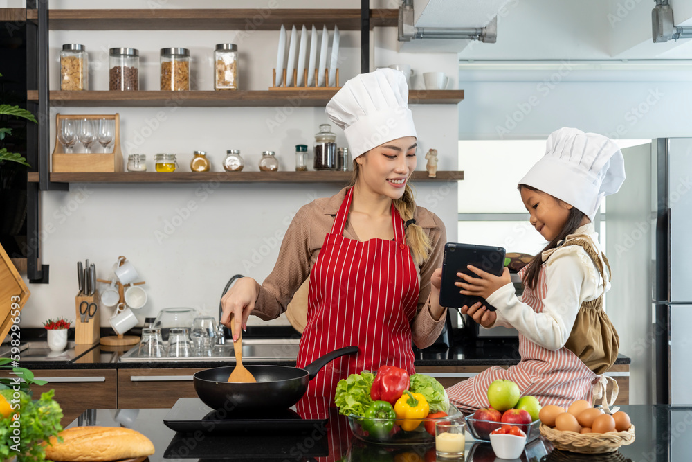Happy Pretty mom and lovely daughter preparing healthy food in kitchen Happy Pretty mom and lovely daughter preparing healthy food in kitchen
