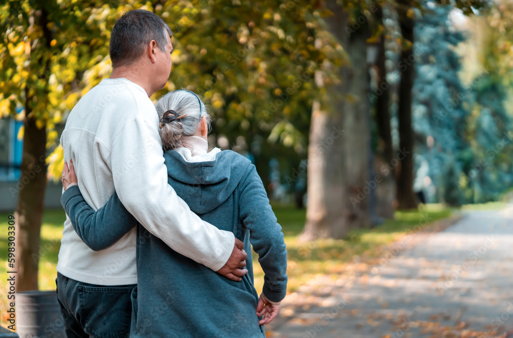 Fototapeta premium An elderly couple, man and woman walk in the autumn park.