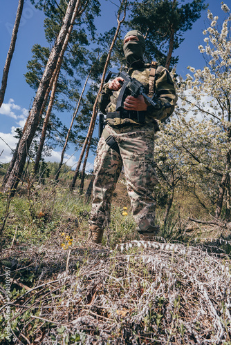 A member of a special unit. A soldier with an assault rifle in his hand and in uniform. Full tactical gear.A soldier in a forest in enemy territory