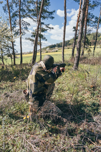 Close-up of a soldier with an assault rifle. A soldier in camouflage guards the area. sniper position. Masked Sniper