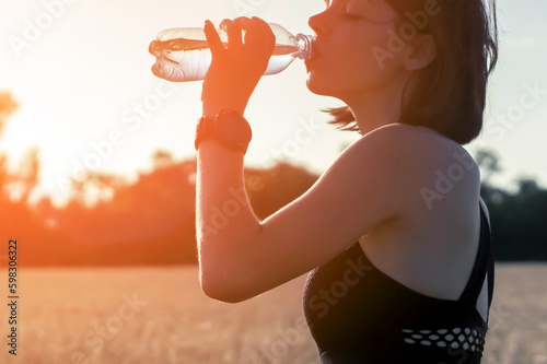 Girl drinks water from a bottle during her training.