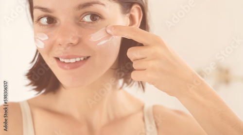 Woman applies a moisturizing cream.