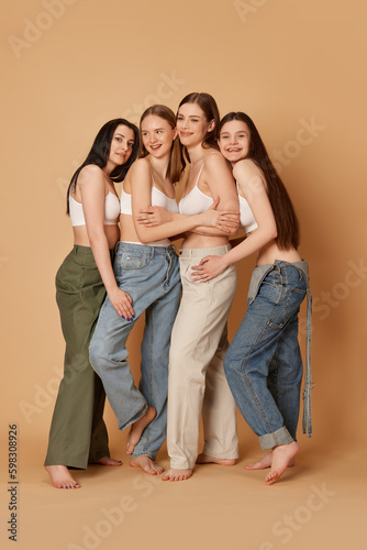 Studio shot with group of young smiling girls wearing casual clothes style posing over beige color background. Fashion style