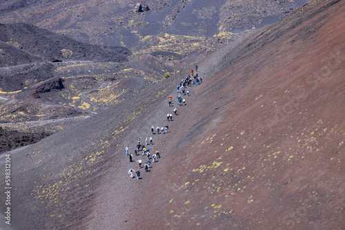 People walking the path of the slopes of Crater Silvestri of volcano Mount Etna, Sicily, Italy photo