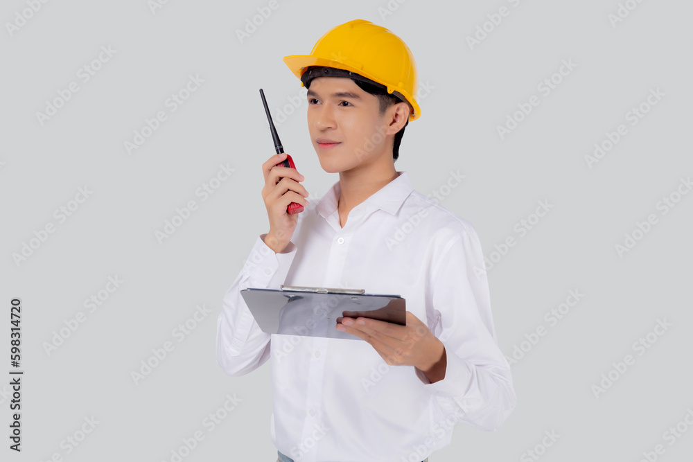 Portrait young asian man is engineer wearing helmet standing and using radio for speak with confident while holding report document isolated on white background, male is architect or contractor. Portrait young asian man is engineer wearing helmet standing and using radio for speak with confident while holding report document isolated on white background, male is architect or contractor.