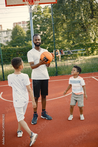Black father with two his multiracial sons playing basketball in basketball court together © prostooleh