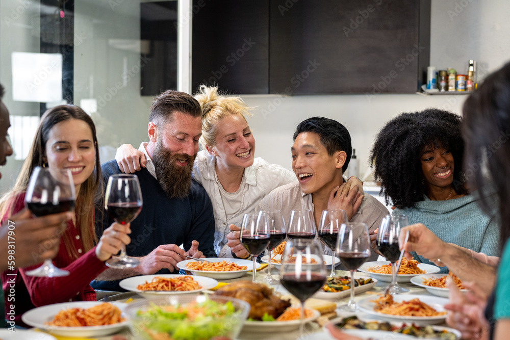 Young friends at the table while eating typical Italian food and spaghetti, meeting to celebrate an event and to be in company, concept of friendship and affective family