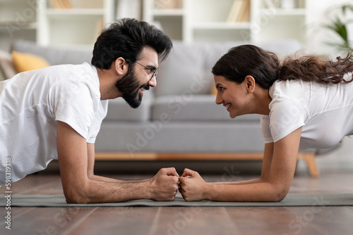 Side view of sporty indian couple making elbow plank exercise at home Generative AI