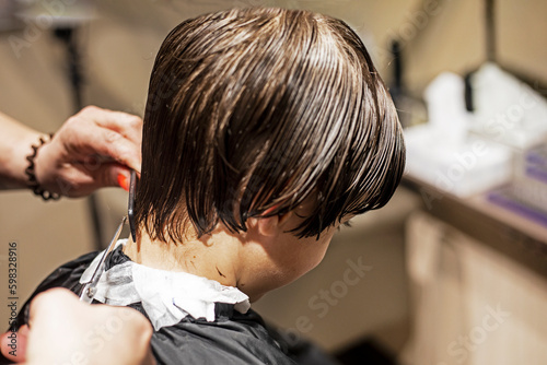 barbershop cuts the tips of wet clean hair at the back of the head with scissors