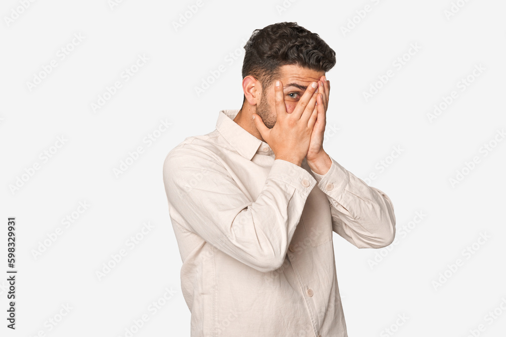 Young handsome man isolated blink through fingers frightened and nervous. Young handsome man isolated blink through fingers frightened and nervous.