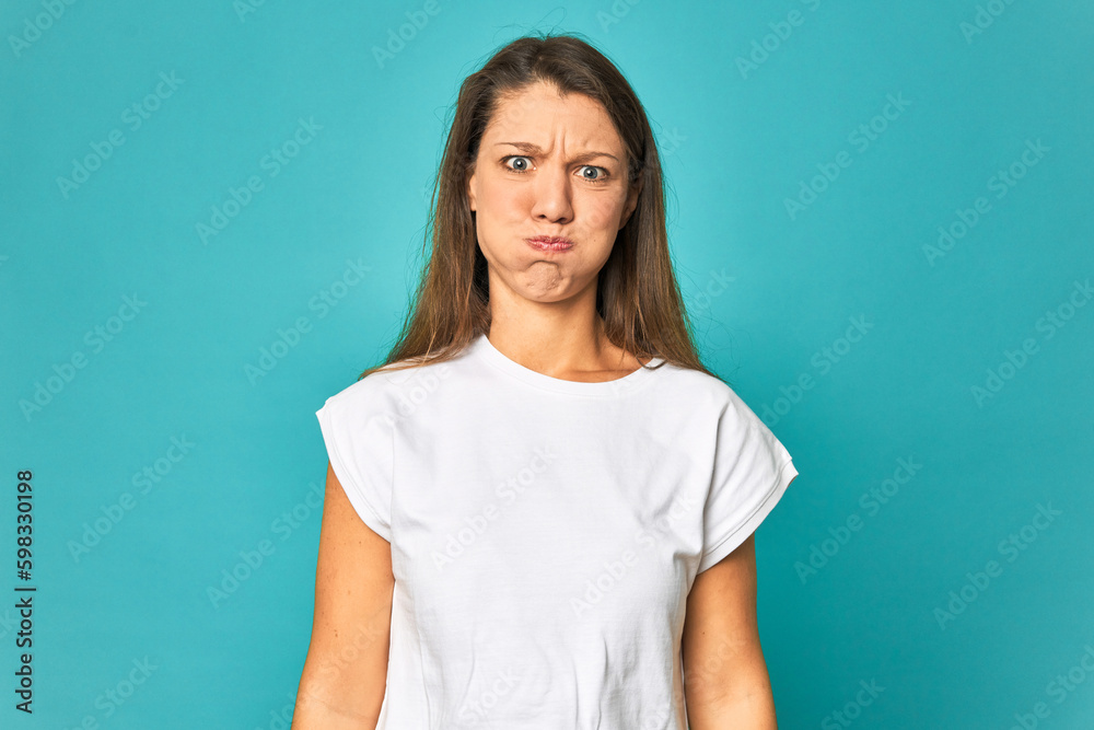 A young caucasian woman isolated blows cheeks, has tired expression. Facial expression concept. A young caucasian woman isolated blows cheeks, has tired expression. Facial expression concept.