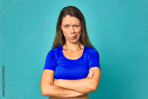 A young caucasian woman isolated frowning face in displeasure, keeps arms folded.