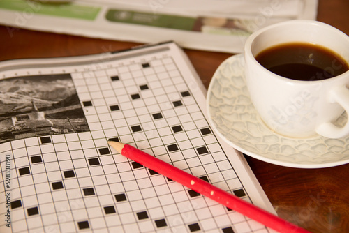 Someone does a crossword as a hobby while having a coffee at a table in a bar