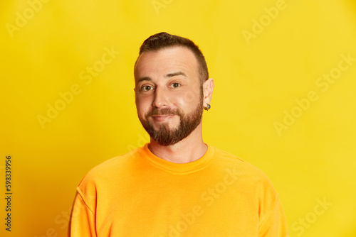Portrait of bearded man with short hair smiling, looking at camera, posing against vivid yellow background. Good news. Concept of human emotions, lifestyle, facial expression, casual fashion. Ad
