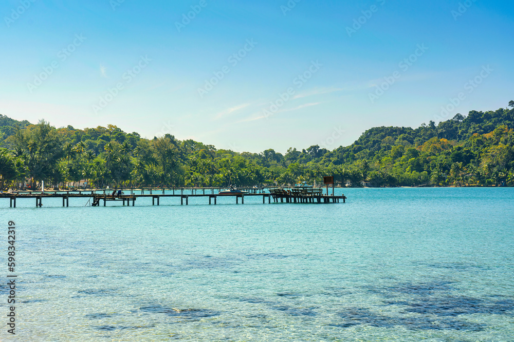 Beautiful tropical sea turquoise water with wooden pier and the forest in sunny day Beautiful tropical sea turquoise water with wooden pier and the forest in sunny day