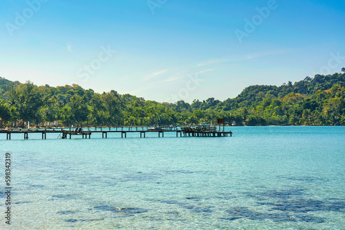 Beautiful tropical sea turquoise water with wooden pier and the forest in sunny day