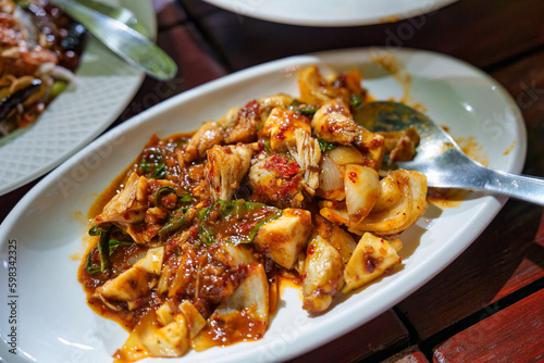 Stir fried chicken meat with chili paste sauce and herbs in white plate