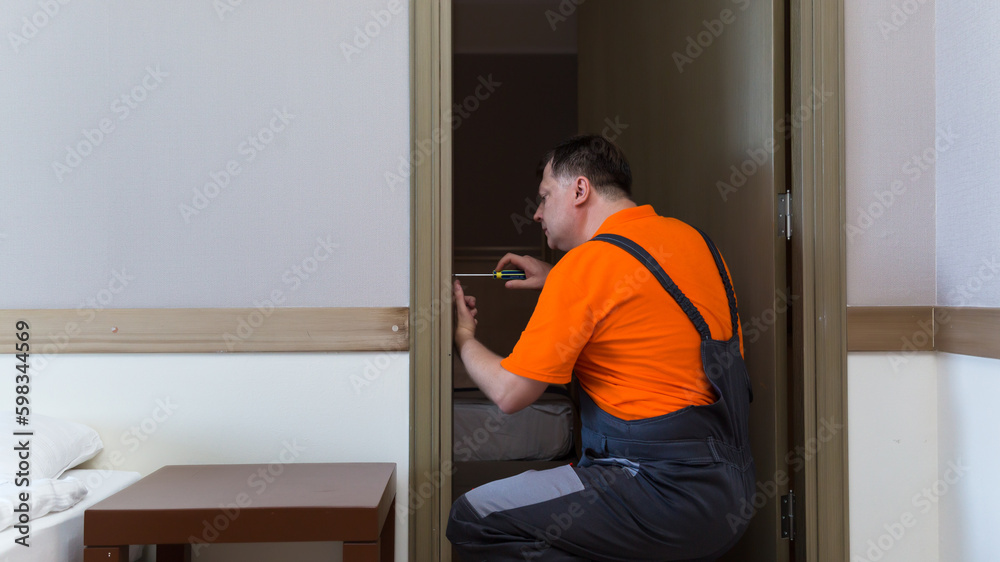 A man is installing a lock on the interior door an apartment.